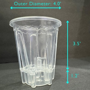 May include: A clear plastic pot with an inner diameter of 3.2 inches and an outer diameter of 4.0 inches. The pot is 3.5 inches tall, with a base that is 1.2 inches high. The pot has a scalloped rim and vertical ridges.