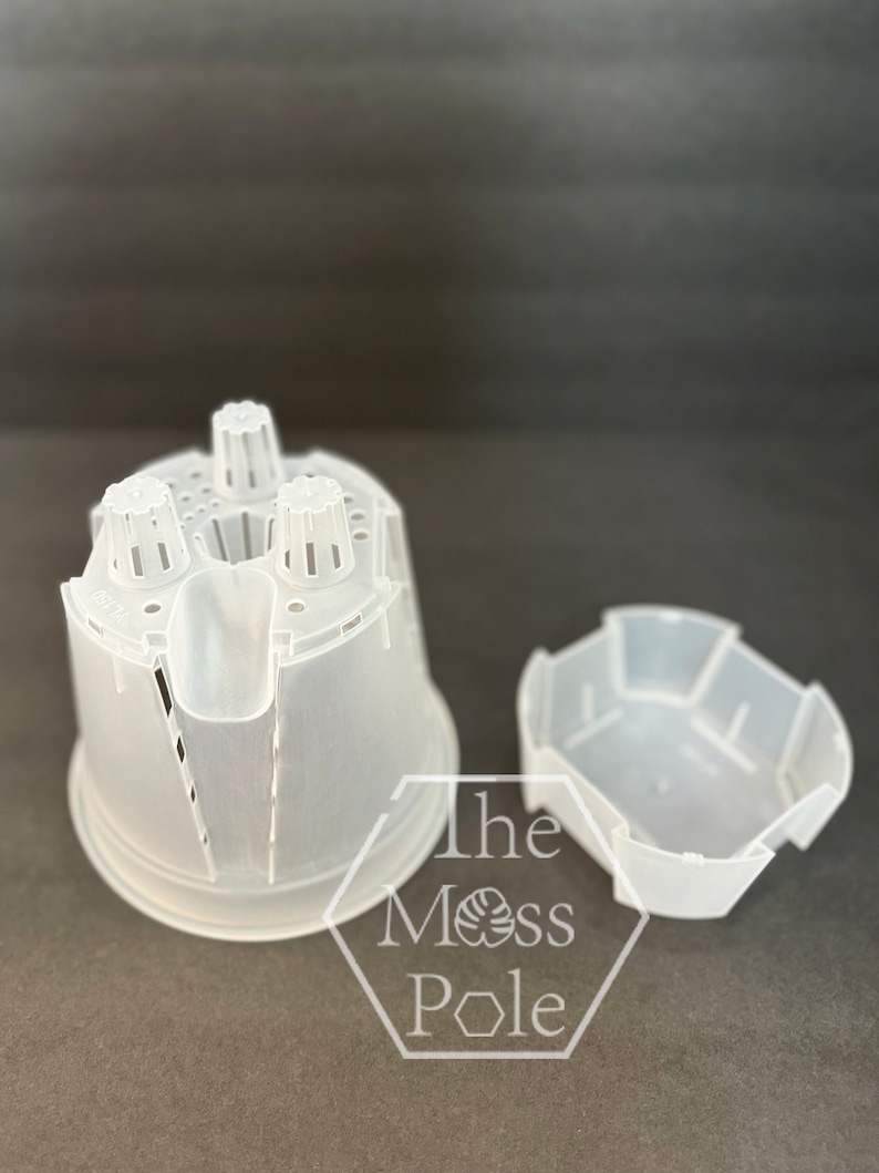 May include: Two clear plastic plant pots, one with a cylindrical shape and drainage holes, and a separate tray. The text "The Moss Pole" is visible on the image.