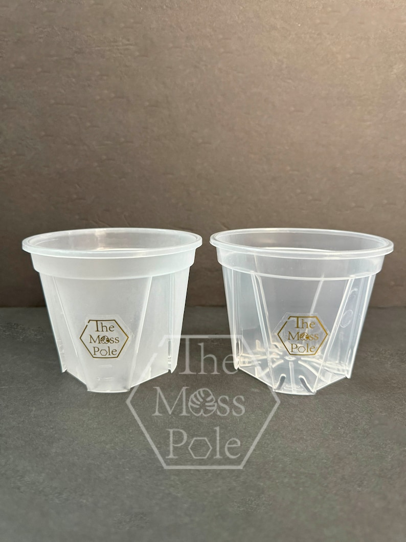 Peut inclure: Deux pots en plastique transparent avec des trous de drainage et un logo hexagonal qui indique "The Moss Pole" au fond de chaque pot.