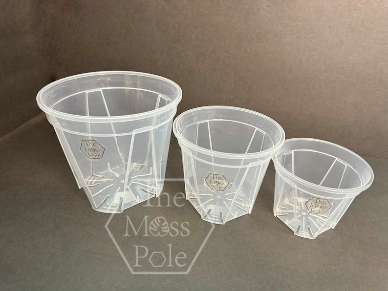 Peut inclure: Trois pots de plantes en plastique transparent avec des trous de drainage et le texte "The Moss Pole" imprim&eacute; au fond de chaque pot.