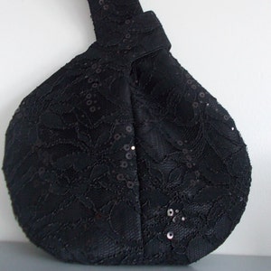 May include: A black lace handbag with sequins. The bag is round and has a knotted handle.