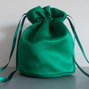 May include: A green satin drawstring bag with a gathered top and long ties.