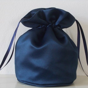 May include: A dark blue satin drawstring bag with long ties. The bag is empty and has a gathered top.