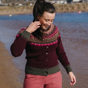 Women on a beach wearing a burgundy fair isle cardigan with pink and green pattern.