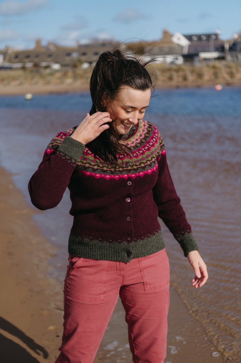 Women on a beach wearing a burgundy fair isle cardigan with pink and green pattern.