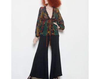 May include: A woman's blouse with a colorful geometric pattern and a long, flowing skirt. The blouse has a V-neckline and long sleeves. The skirt is black and has a wide leg.