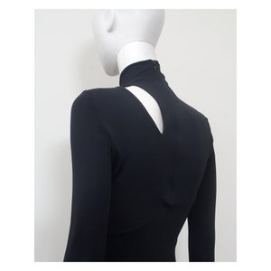 May include: Black long-sleeved dress with a high mock neck and a keyhole cutout in the back.