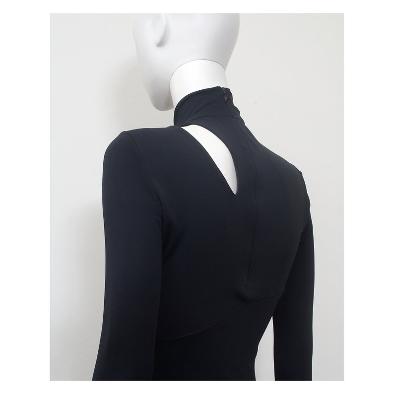May include: Black long-sleeved dress with a high mock neck and a keyhole cutout in the back.