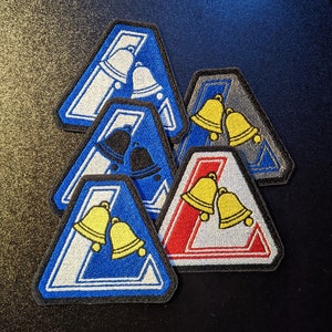 May include: Five iron-on patches in the shape of triangles with a white, blue, red, and gray background. Each patch features two bells with different colors and designs.