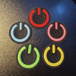 Puede incluir: Cinco parches bordados para planchar en forma de interruptor de encendido/apagado. Los parches son rojo, azul, rosa, verde y amarillo.