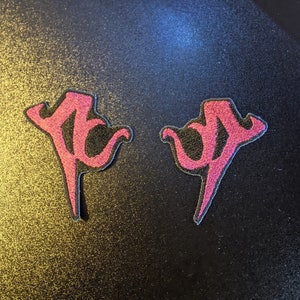 May include: Two pink embroidered patches in the shape of a stylized letter "Y" on a black background.