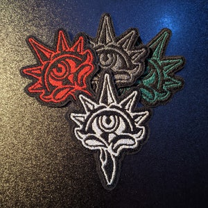 May include: Four embroidered patches with a spiky, flower-like design. Each patch features a different color scheme: red, black and white, gray, and green.