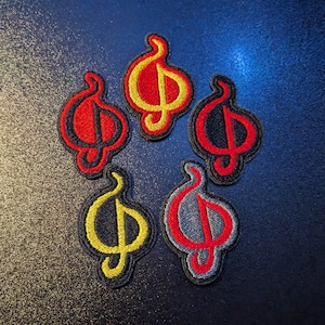 Op de afbeelding: Zes geborduurde patches in de vorm van een gestileerde letter 'S' met een vlamontwerp. De patches zijn in verschillende kleuren, waaronder rood, geel, zwart en grijs.