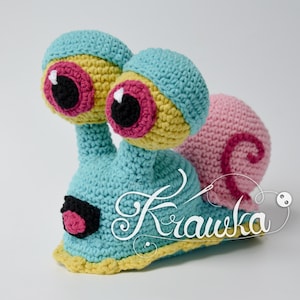 May include: A crocheted snail toy with a blue body, yellow accents, pink shell, and large black eyes with pink eyelids.