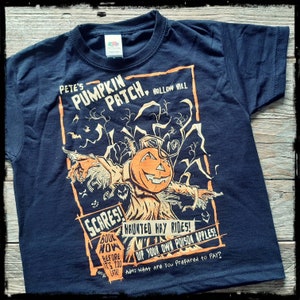 May include: Black t-shirt with a vintage-style illustration of a scarecrow with a pumpkin head. The text on the shirt reads "Pete's Pumpkin Patch. Hollow Hill. Scares! Book Now Before It's Too Late! Haunted Hay Rides! Dip Your Own Poison Apples! Adm: What Are You Prepared to Pay?"