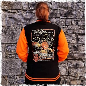 May include: Black and orange baseball jacket with a Halloween-themed design on the back. The design features a pumpkin patch with a scarecrow and the text "Pete's Pumpkin Patch, Hollow Hill".