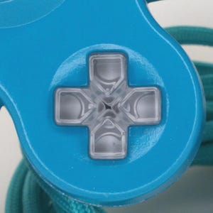 May include: Close-up of a light blue video game controller with a clear, gray directional pad. A teal-colored cord is visible in the background. The controller's design is simple and modern, with a focus on functionality.
