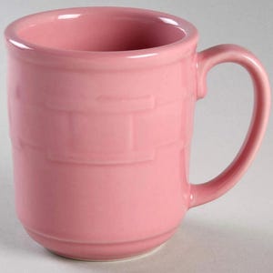 May include: A solid pink ceramic mug featuring a smooth, glossy finish and a subtle, raised horizontal band pattern encircling the exterior. The mug has a sturdy, curved handle on the right side and a wide, circular rim with a thick, rounded edge.