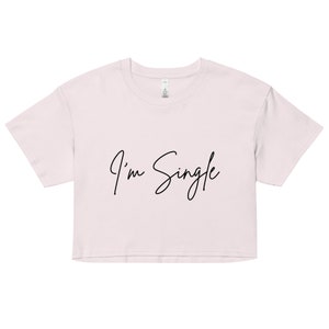 May include: A light pink cropped t-shirt with the text "I'm Single" written in black cursive.