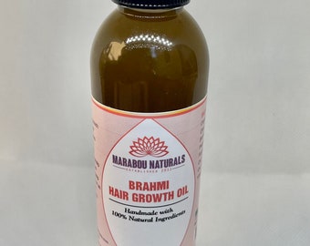 May include: A 6 ounce bottle of Brahmi Hair Growth Oil by Marabou Naturals. The bottle is brown glass with a black cap and a clear dropper. The label is pink and white with a lotus flower design. The label reads "Handmade with 100% Natural Ingredients".