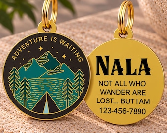 May include: Two round gold-toned metal pet tags with split rings. One tag features a black and teal mountain landscape graphic with the text ADVENTURE IS WAITING. The other tag is gold with black text reading NALA, NOT ALL WHO WANDER ARE LOST... BUT I AM, and 123-456-7890.