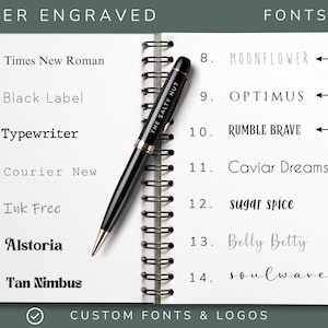 May include: A spiral-bound notebook page displaying a list of fourteen numbered laser engraved font options, including Times New Roman, Black Label, Typewriter, Courier New, Ink Free, Alstoria, Tan Nimbus, Moonflower, Optimus, Rumble Brave, Caviar Dreams, sugar spice, Belly Betty, and soulwave, with a black pen featuring the text THE SALTY HUT resting diagonally across the centre.