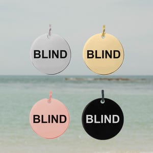 May include: Four round metal tags with the word "BLIND" printed in black. The tags are in silver, gold, rose gold, and black.
