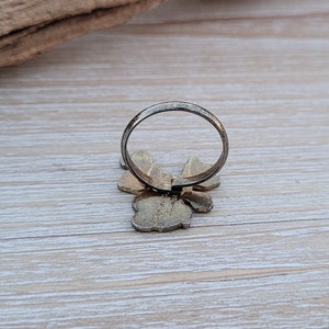 May include: A silver ring with a gold butterfly design. The butterfly has a textured surface and the ring is open on the back.