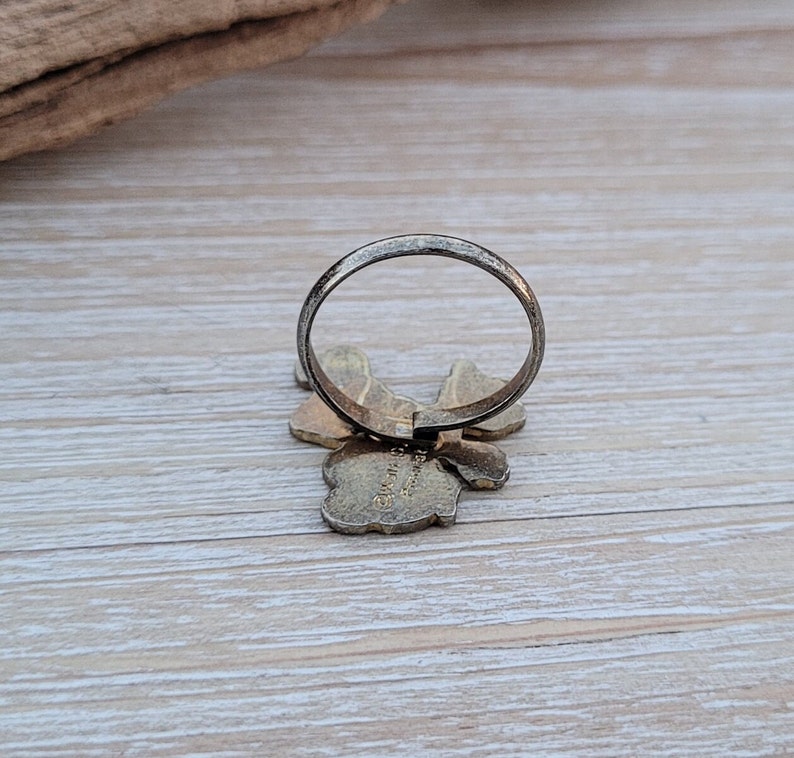 May include: A silver ring with a gold butterfly design. The butterfly has a textured surface and the ring is open on the back.