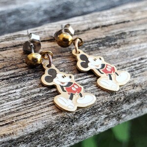 Puede incluir: Un par de pendientes de Mickey Mouse de tono dorado. Los pendientes presentan una imagen de dibujos animados de Mickey Mouse con su caracter&iacute;stico pantal&oacute;n rojo y guantes blancos. Los pendientes est&aacute;n unidos a postes de plata.