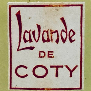 Pu&ograve; includere: Un'etichetta bianca con un bordo rosso e il testo "Lavande de COTY" in lettere rosse.