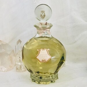 K&ouml;nnte beinhalten: Eine Vintage-Glasflasche mit Eau Sauvage von Coty Parfum. Die Flasche ist klar und hat eine strukturierte Oberfl&auml;che. Das Etikett ist goldfarben und rosa mit dem Text "Eau Sauvage Coty".