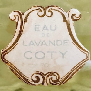 K&ouml;nnte beinhalten: Ein Vintage-Etikett f&uuml;r Coty Eau de Lavande Parfum. Das Etikett ist wei&szlig; mit goldenen Verzierungen und tr&auml;gt den Text "Eau de Lavande Coty" in einer dekorativen Schrift.