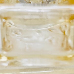 May include: A clear glass bottle stopper with a decorative design of a floral motif. The stopper is designed to fit a bottle of wine or liquor.