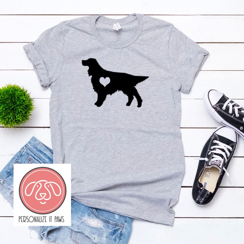 K&ouml;nnte beinhalten: Ein graues T-Shirt mit einer schwarzen Silhouette eines Hundes mit einem wei&szlig;en Herzen in seiner Brust. Der Text "PERSONALIZE IT PAWS" befindet sich am unteren Rand des Bildes.