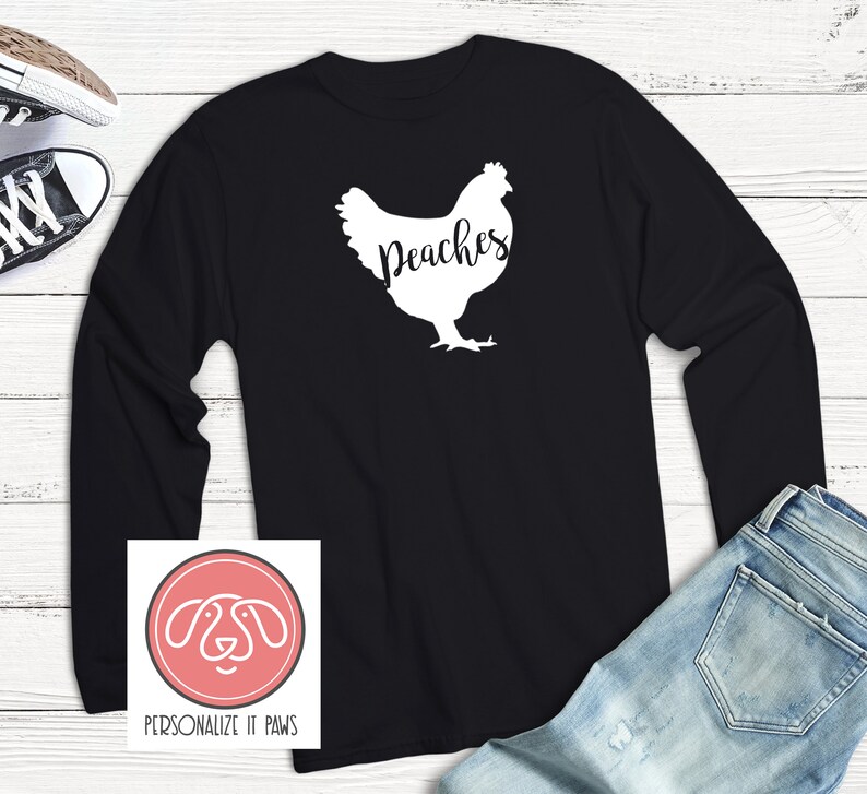 May include: Black long-sleeve shirt with a white silhouette of a chicken and the text "Peaches".