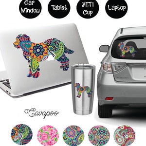 May include: A colorful paisley pattern Cavoodle dog silhouette sticker. The sticker is shown on a laptop, Yeti cup, and car window. The sticker is also available in five different paisley patterns.