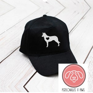May include: Black baseball cap with a white silhouette of a Collie dog with a heart on its chest. The text "PERSONALIZE IT PAWS" is below the image of the dog.