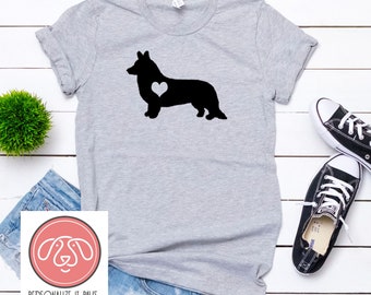 May include: A gray t-shirt with a black silhouette of a corgi with a white heart on its chest. The text "PERSONALIZE IT PAWS" is on a pink circle below the image.