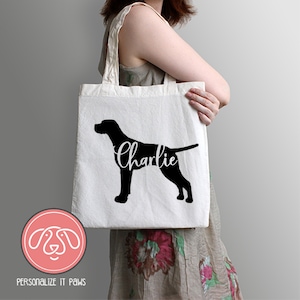 May include: White canvas tote bag with a black silhouette of a dog and the name "Charlie" printed in white cursive.