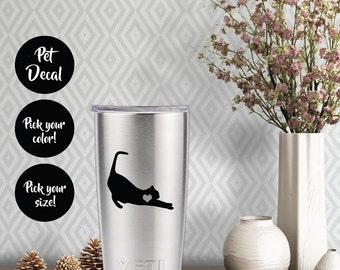 Könnte beinhalten: Ein silberner Yeti-Becher mit einem schwarzen Katzen-Silhouetten-Aufkleber. Der Aufkleber zeigt ein Herz auf der Brust der Katze. Der Text "Pet Decal" ist in einem schwarzen Kreis über dem Becher sichtbar. Zwei weitere schwarze Kreise mit dem Text "Wählen Sie Ihre Farbe!" und "Wählen Sie Ihre Größe!" sind unter dem Becher sichtbar.