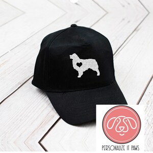 May include: Black baseball cap with a white silhouette of an Australian Shepherd with a heart on its chest. The text "PERSONALIZE IT PAWS" is below the image.
