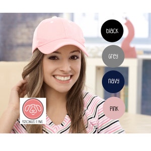 May include: A pink baseball cap with a curved brim and a white logo on the front. The logo says "Personalize It Paws".