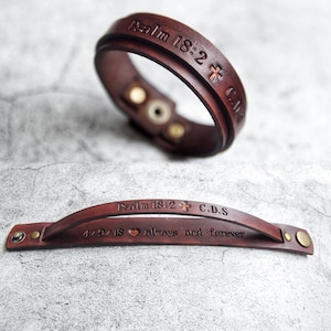 Könnte beinhalten: Zwei braune Lederarmbänder mit eingraviertem Text. Das obere Armband trägt den Text "Psalm 18:2 + C.D.S.". Das untere Armband trägt den Text "Psalm 18:2 + C.D.S. 4/9/18 ♥ für immer und ewig".