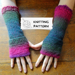 May include: Knitted arm warmers in pink, green, and blue. The cuffs are ribbed. The image shows the arm warmers on a wooden surface. The text "KNITTING PATTERN" is included with a graphic of yarn and needles.