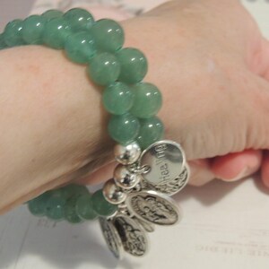 May include: A green jade stone bracelet with silver charms. The charms have the word "healing" engraved on them.