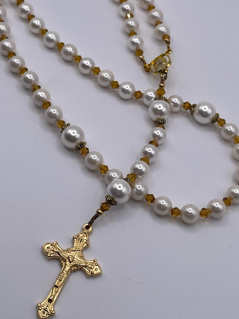 Rosario con crucifijo dorado, perlas blancas y cristales color champán. imagen 3