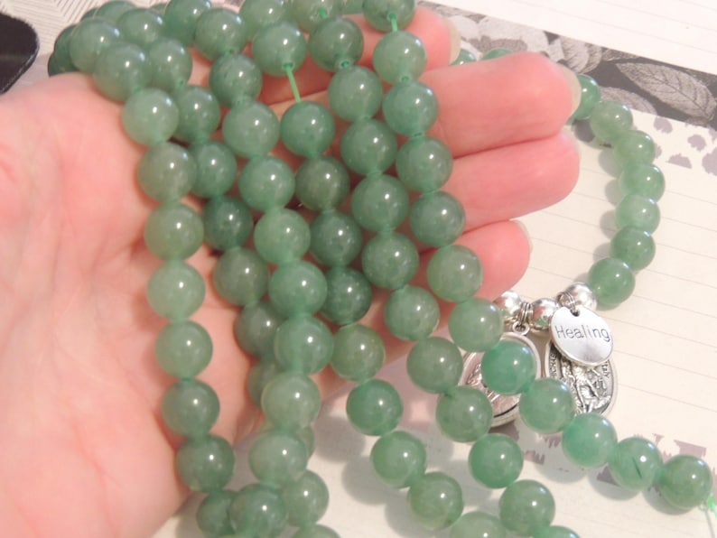 May include: A green jade beaded mala necklace with a silver charm that says "Healing".
