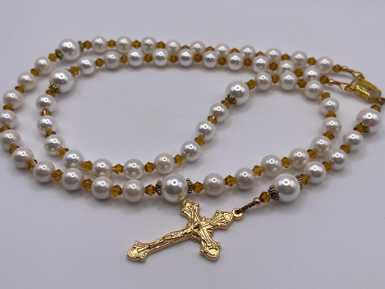 Rosario con crucifijo dorado, perlas blancas y cristales color champán. imagen 1