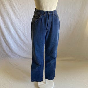 May include: Dark blue denim jeans with a high waist and straight leg. The jeans have a button and zipper closure, front pockets, and belt loops. The jeans are displayed on a mannequin.